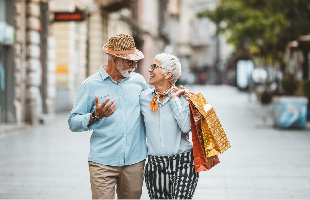 55+ Communities older couple walking with shopping bags