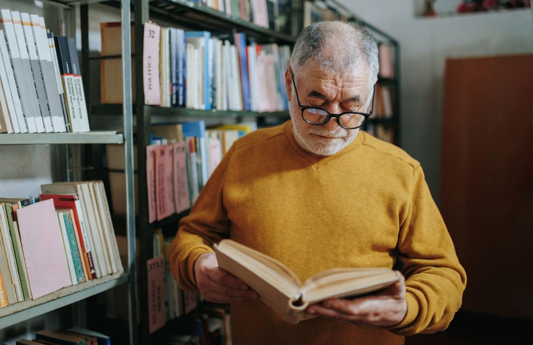 Guides Older man reading a book in library