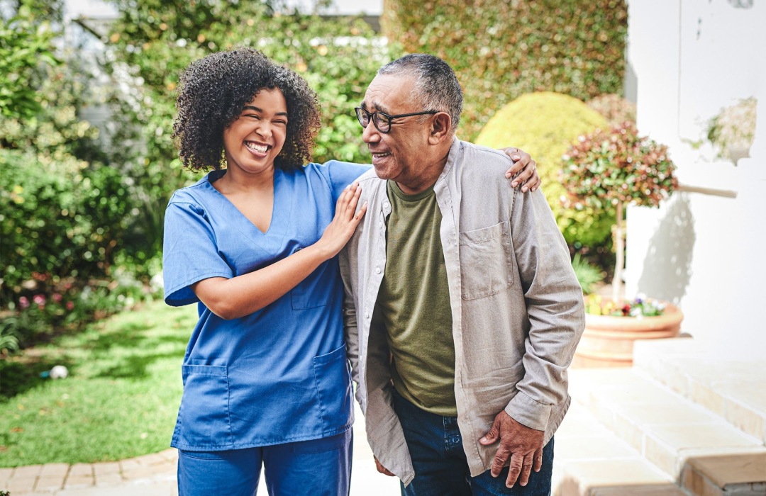 Nurse walking a resident in the garden 