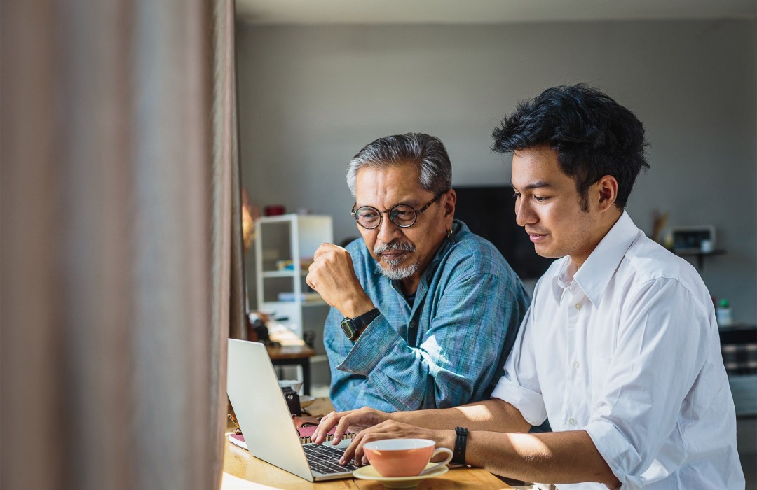 Adult son helping his father on the laptop